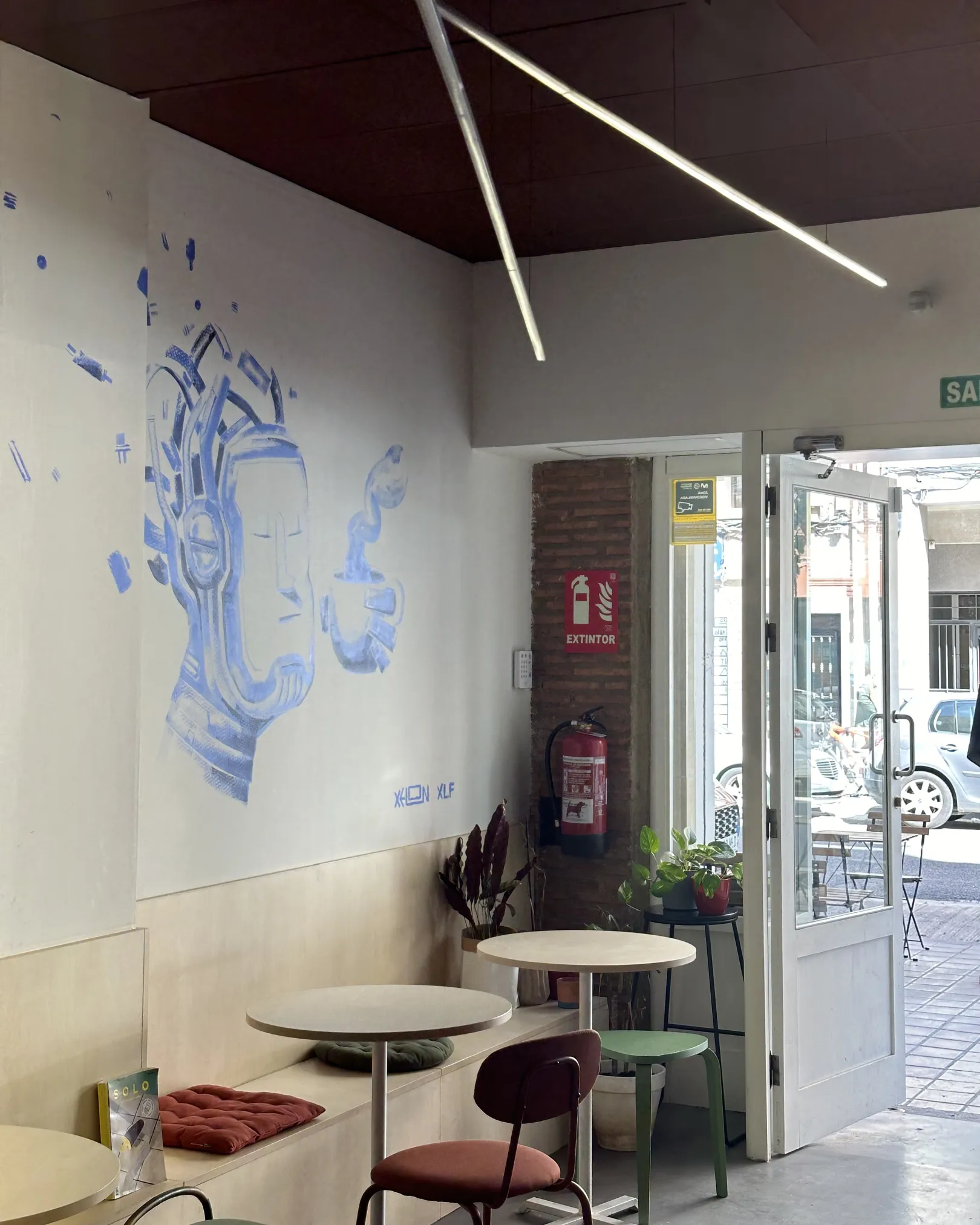 Blue mural above banquette seating and round tables inside Kaide Coffee, El Cabanyal, Valencia