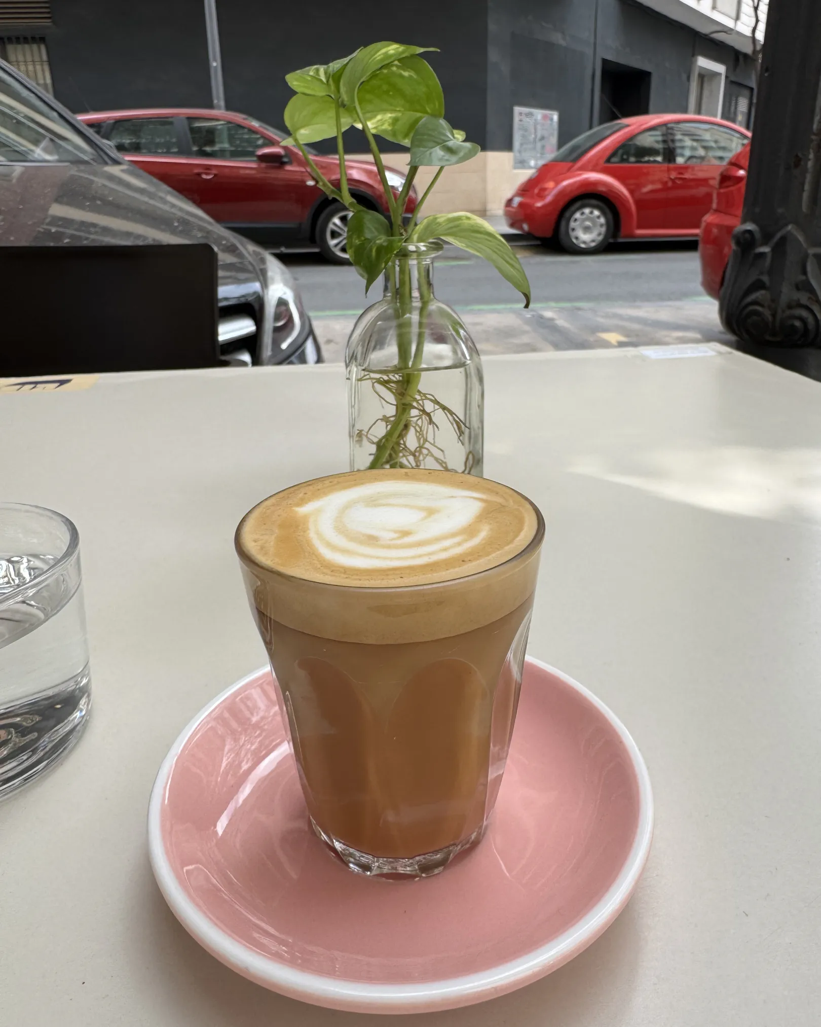 Cortado in a glass on a pink saucer at a terrace table outside Let It Bloom, Ruzafa, Valencia
